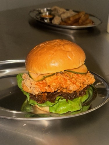 Buffalo Butter fried chicken sandwich with confit onions and buffalo butter sauce on a brioche bun